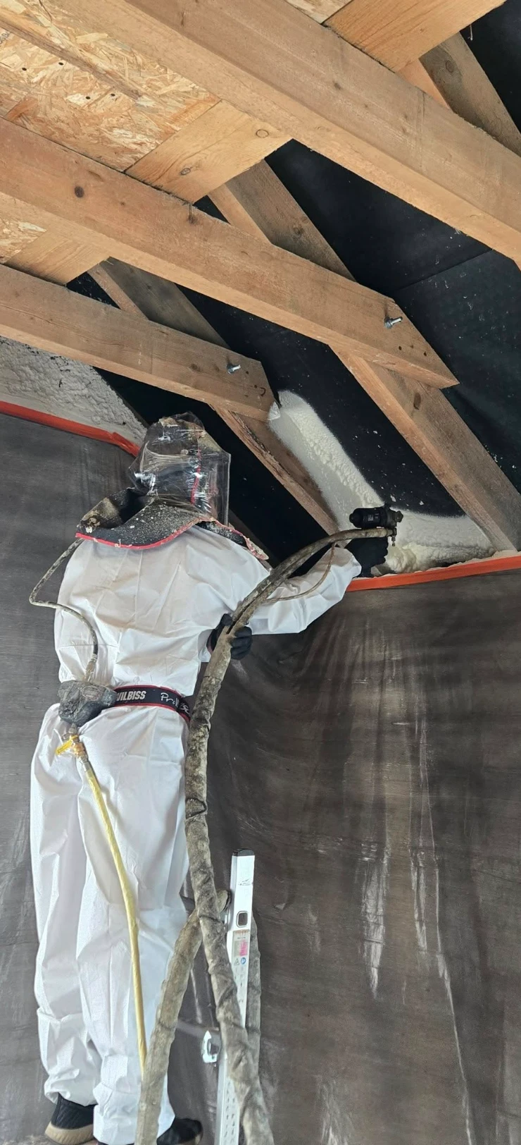 Pracownik rozkładający pianę na&nbsp;poddaszu